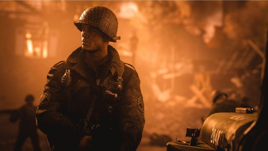 兵士が彼の後ろに燃えている建物を持って立っています。