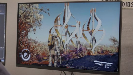 Starfield トレーラー: Starfield のゲーム内映像を表示する PC モニター。宇宙服を着た人が背の高いらせん構造の前に立っています。
