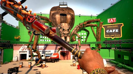 Dead Island 2 のレビュー: Dead Island 2 PS5 のスクリーンショットで、巨大なクモがいる映画のセットでキャラクターが改造されたコウモリを振り回している様子を示しています