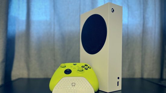 Xbox Series S レビュー: 白い Xbox Series S 本体が縦に立っていて、その前に緑のコントローラーと白のコントローラー スタンドがある